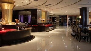Eine Hotellobby mit einer Rezeption, einer großen Säule und einem Essbereich mit Stühlen.