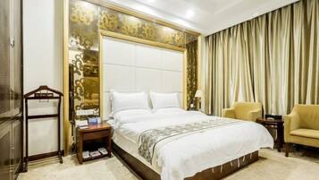 A hotel room with a large bed, a wooden nightstand, a chair, and a curtain.