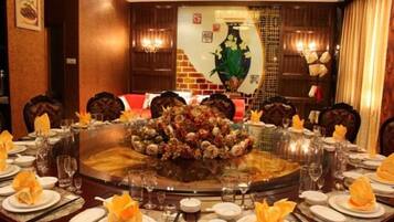 A round dining table with a floral centerpiece, surrounded by chairs and set with plates, glasses, and napkins.
