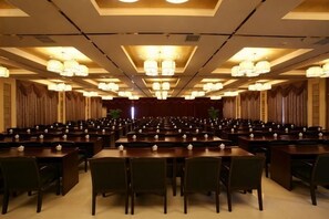 A conference room with rows of tables and chairs, large chandeliers, and a stage at the front. - Xianning Chutian Yaochi Hot Spring Resort (Xianning)
