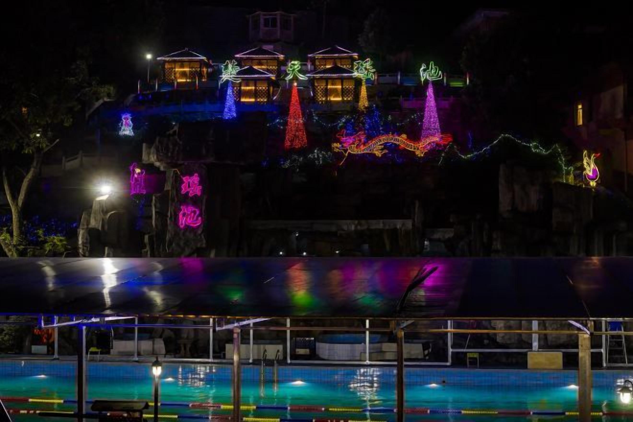A building with illuminated decorations, a pool area, and a covered seating area.