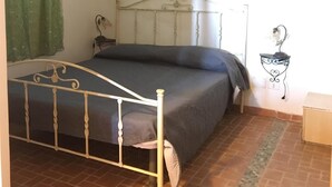 A bedroom with a metal bed frame, a single bed, a bedside table, a wall-mounted air conditioner, and a small decorative plant. - VIILLA PAOLA 4 beds, private garden in the Residence Villa Carla (Vieste)