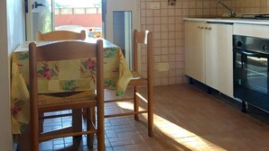 A kitchen with a tiled backsplash, a stove, and a dining area with a table and chairs. - VIILLA PAOLA 4 beds, private garden in the Residence Villa Carla (Vieste)