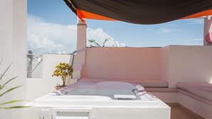 Een dakterras met een jacuzzi, een zitgedeelte en een potplant.