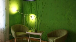 Una habitación con dos sillones verdes, una mesita y una pared verde con un diseño.