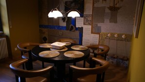 Una mesa de comedor redonda con individuales tejidos, seis sillas de cuero y un objeto rectangular en el centro.