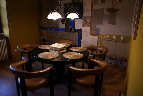 Una mesa de comedor redonda con individuales tejidos, seis sillas de cuero y un objeto rectangular en el centro.