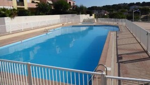 En swimmingpool med et hvidt hegn, omgivet af bygninger.