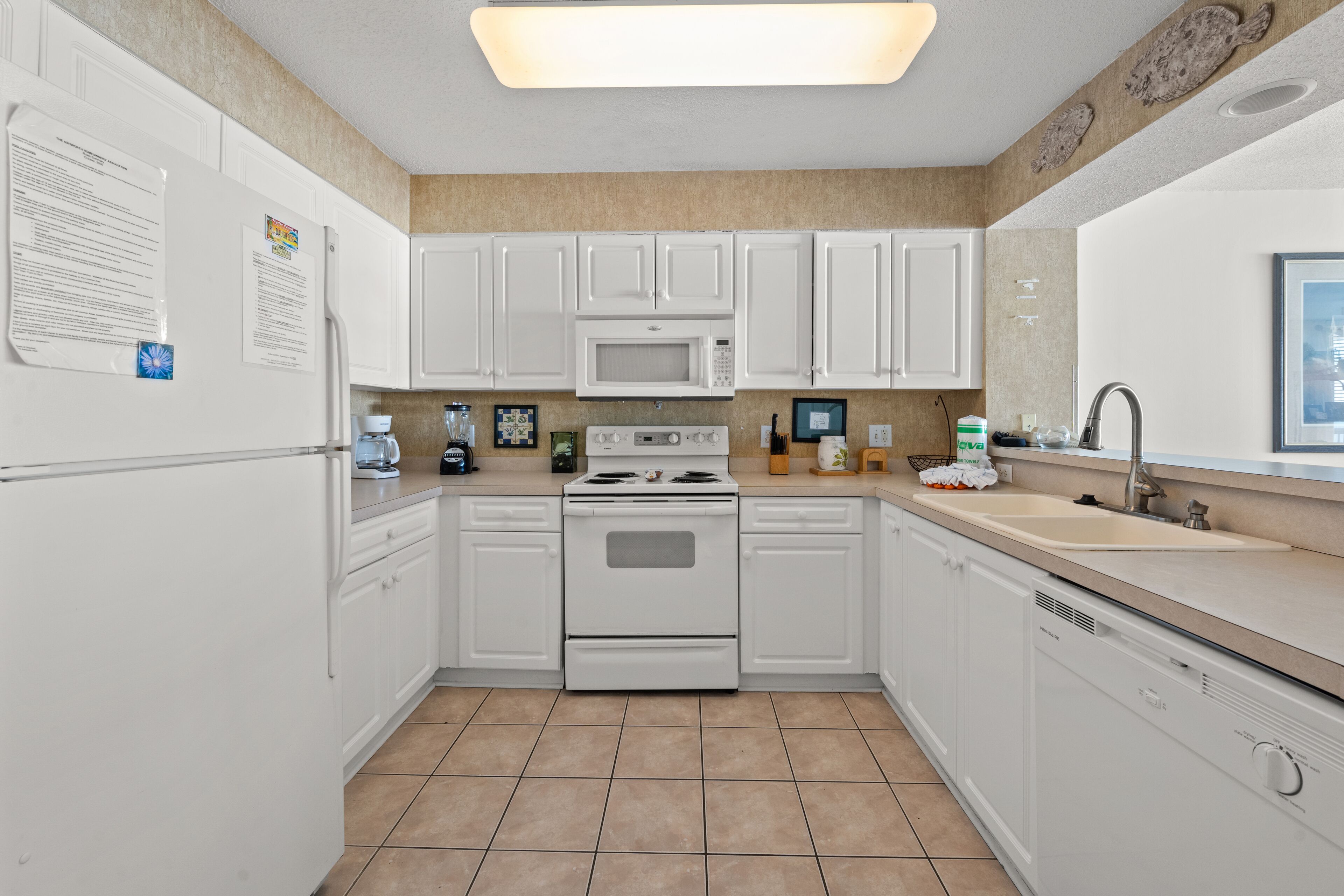 A modern kitchen with white cabinets, a microwave, stove, and a dishwasher.