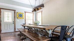 A dining area with a wooden table and benches, black chairs, and a hanging light fixture. - Sleeps 16-Marina, Pool, Roaring River & Table Rock (Cassville)