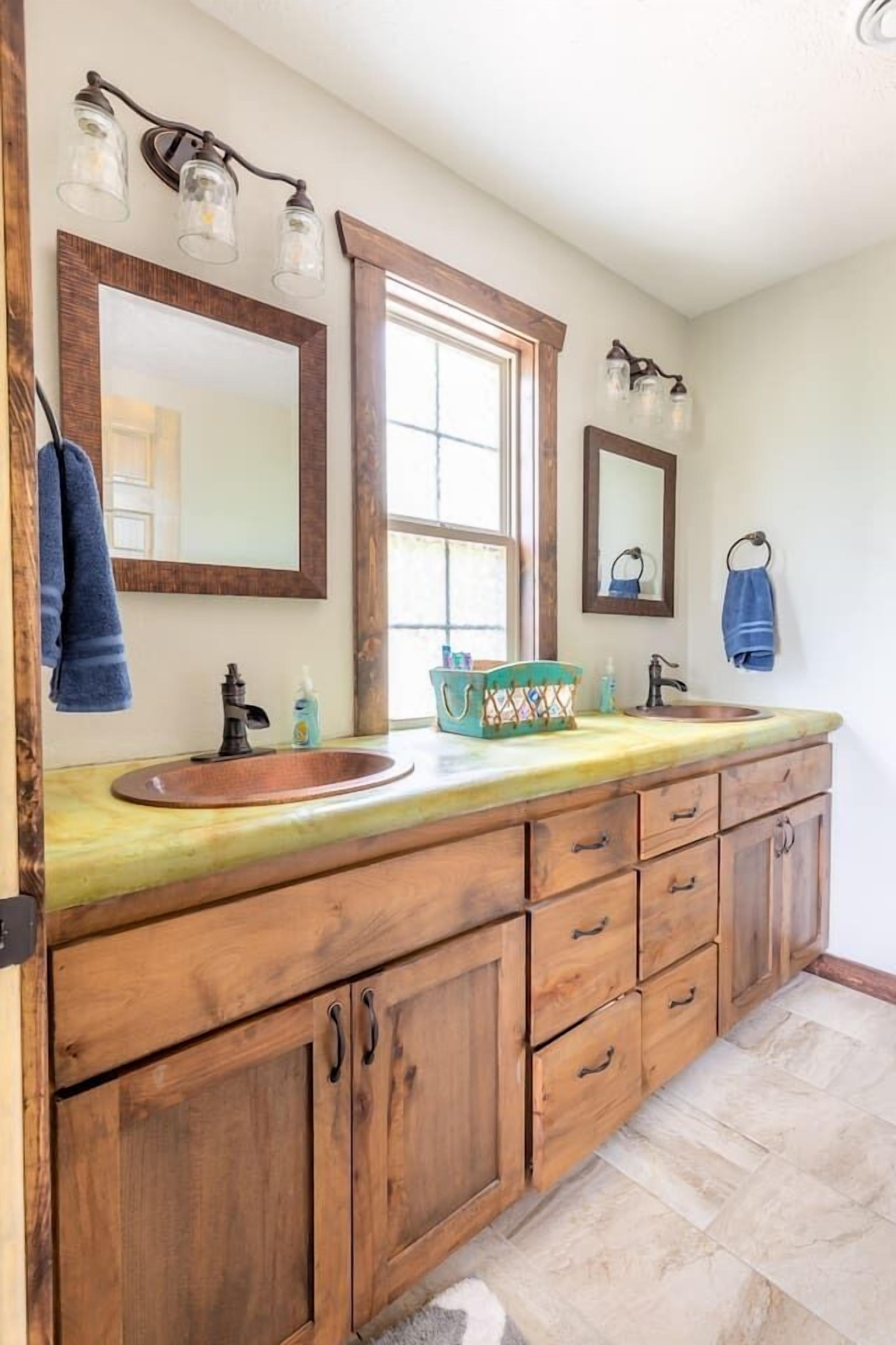 Une salle de bain avec un meuble-lavabo en bois, deux vasques et un grand miroir.