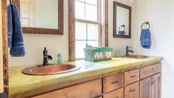 Une salle de bain avec un meuble-lavabo en bois, deux vasques et un grand miroir.