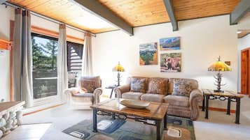 A living room with a sofa, coffee table, and lamps. There is a sliding glass door leading to an outdoor area.
