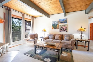 A living room with a sofa, coffee table, and lamps. There is a sliding glass door leading to an outdoor area. - Sundowner Last Run Condo: Ski-In, 2 Blocks To Main St (Breckenridge)