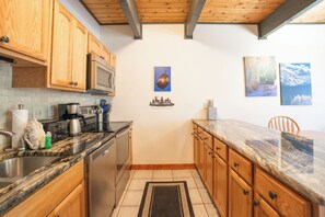 A kitchen with wooden cabinets, a microwave, a stove, and a coffee maker. - Sundowner Last Run Condo: Ski-In, 2 Blocks To Main St (Breckenridge)