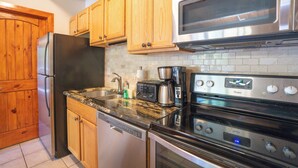 Una cocina con armarios de madera, un refrigerador de acero inoxidable, un microondas, un tostador y un lavavajillas.