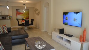 A modern living room with a sofa, dining table, and TV. - Fort Myers Luxury Vacation Condo (Fort Myers)