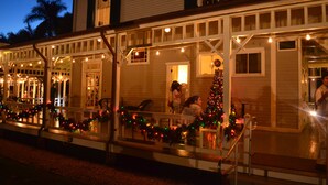 A building with a porch decorated with Christmas lights and garlands, a Christmas tree, and a staircase leading to the entrance. - Fort Myers Luxury Vacation Condo (Fort Myers)