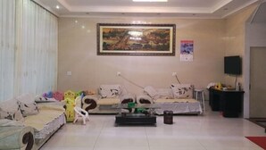 A living room with a sofa set, a coffee table, a TV, and a painting on the wall. - Jinmalou Hotel (Yueqing)