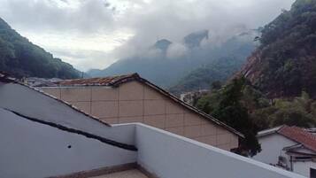 Ein Gebäude mit flachem Dach und einer Kachelwand, umgeben von Grünflächen und Bergen.
