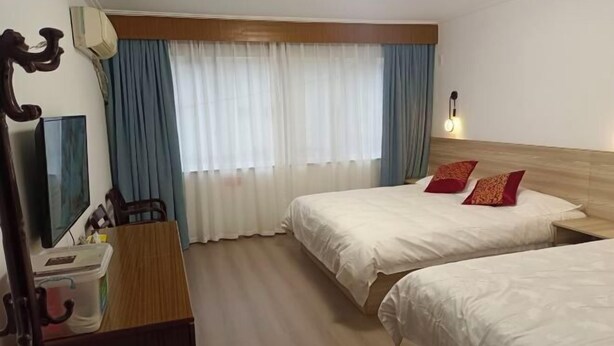 A hotel room with two beds, a desk, a chair, a TV, and a window with curtains. - Jinmalou Hotel (Yueqing)