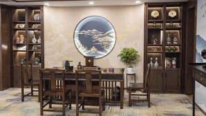 Un coin repas avec une table ronde, des chaises en bois et des étagères ornées d’objets décoratifs.