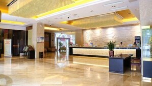 Un hall d’hôtel avec un comptoir d’accueil, un lustre et un mur en pierre.