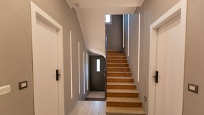 A modern hallway with a wooden staircase leading to a dark room. - Relax nel verde (Segrate)