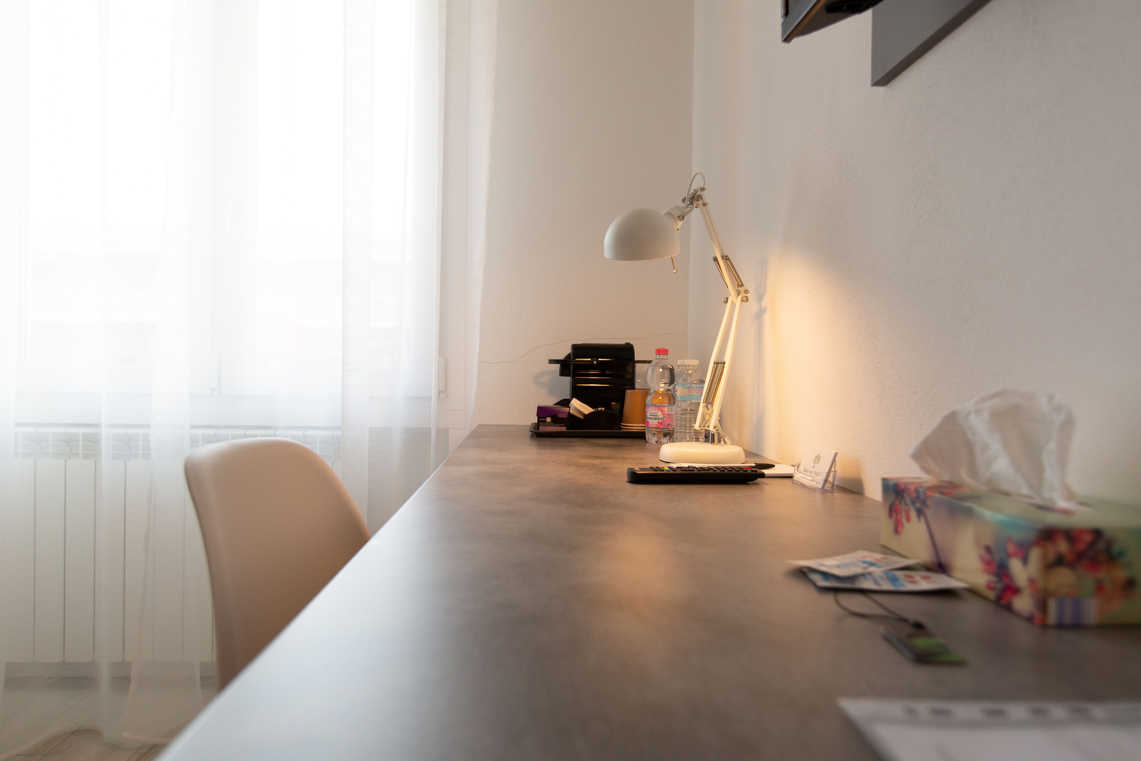 Ein modernes Zimmer mit einem Holztisch, einer Lampe, einer Flasche, einer Taschentuchbox und einem Stuhl.
