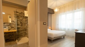 A bedroom with a bed, a desk, and a shower area with a stone wall. - Relax nel verde (Segrate)
