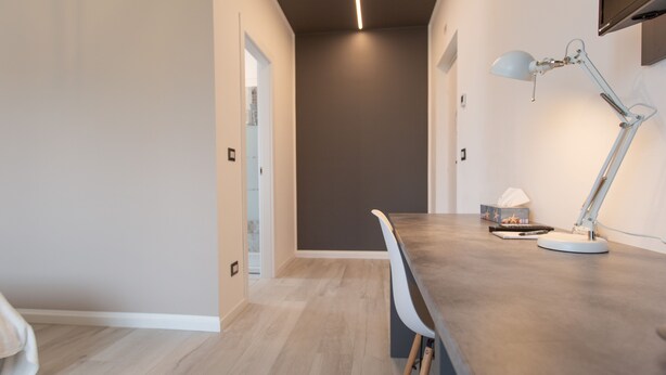 A modern kitchen with a wooden countertop, a white chair, and a table lamp. - Relax nel verde (Segrate)