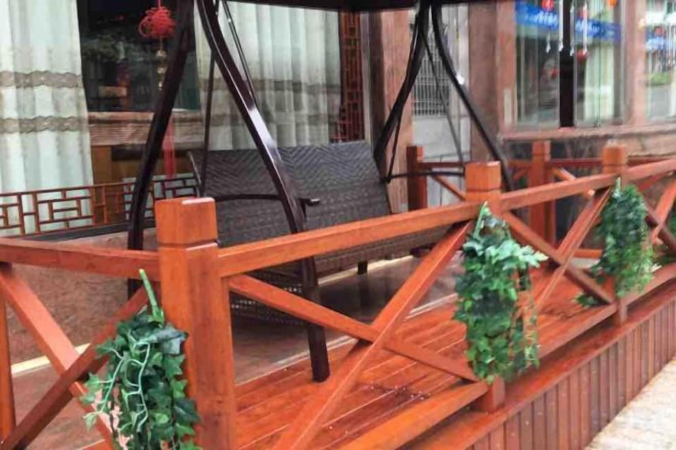 A wooden deck with chairs and a railing, overlooking a street.