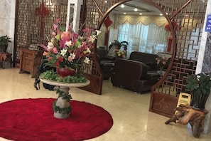 A lobby with a red carpet, a floral centerpiece, and a traditional Asian-style partition. - Mingyan Hotel (Yueqing)