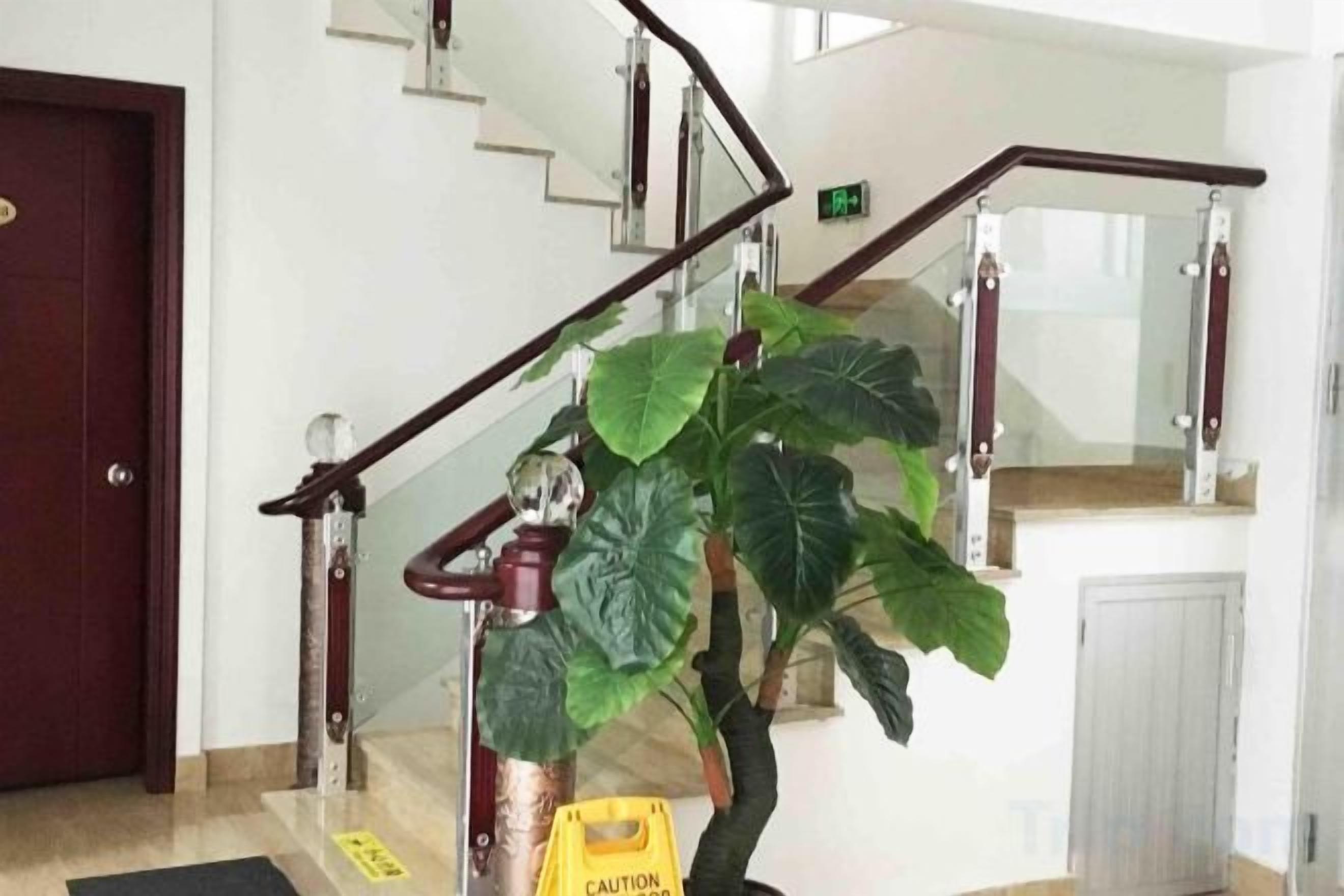 Una escalera con barandilla, una señal de precaución y una planta en maceta.