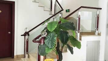 Una escalera con barandilla, una señal de precaución y una planta en maceta.