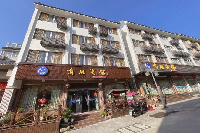 A multi-story building with a ground-level entrance, balconies, and signage indicating a hotel and a restaurant.