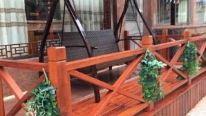 Eine Holzterrasse mit einer Schaukel und Zierpflanzen.