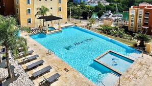 Une piscine agrémentée d’une pergola, de chaises longues et offrant une vue sur un port de plaisance et des immeubles de grande hauteur.