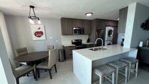 Une cuisine moderne dotée d’un îlot central, d’appareils électroménagers intégrés et d’un coin repas avec une table et des chaises.