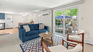 A living room with a blue sofa, a round wooden coffee table, and a white armchair. - Minutes to Nauset Beach, Central AC, Game Space! (Orleans)