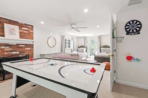 A room with a foosball table, a dartboard, and a bed with a patterned headboard. - Minutes to Nauset Beach, Central AC, Game Space! (Orleans)