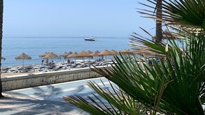 Une plage avec des parasols, des chaises longues et une vue sur la mer.