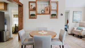 Un comedor con una mesa redonda de madera, cuatro sillas grises tapizadas y una vela en el centro.