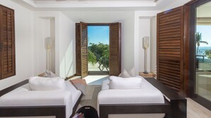 Une chambre d’hôtel avec deux lits, un ventilateur de plafond et vue sur la plage.