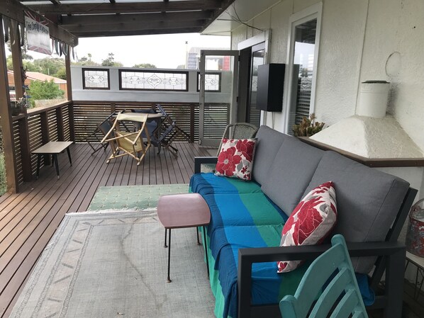A covered outdoor seating area with a sofa, chairs, and a table. - Funky 50's beach house (Otaki Beach)