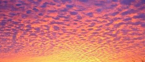 A sunset with a clear sky and silhouettes of distant hills.