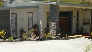 A modern house with a stone pillar, a satellite dish, and a red door. - Waterviews and relaxation (Paihia)