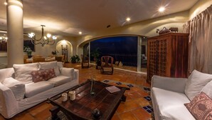 A spacious living area with a white sofa, a wooden coffee table, and a view of the night sky through a glass door.