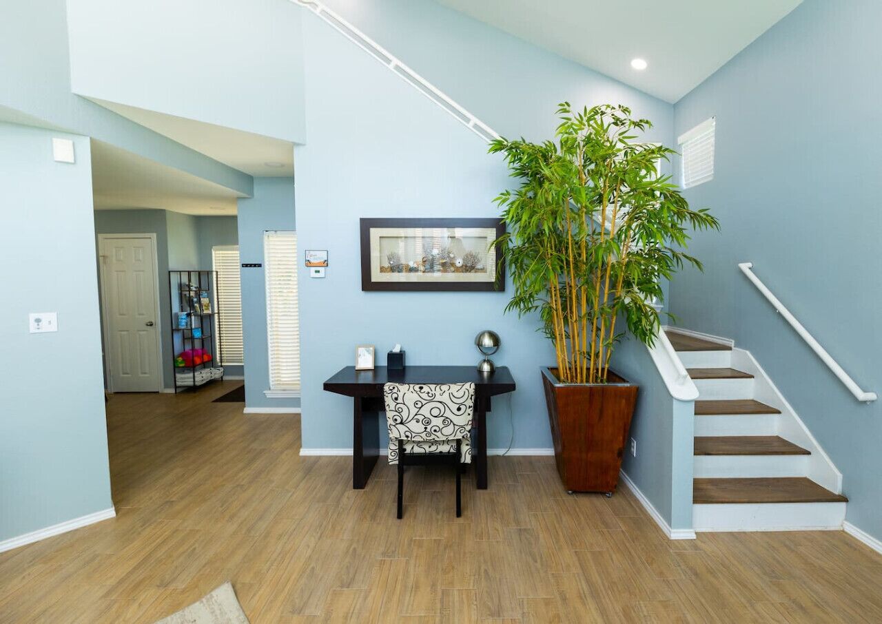 Un interior moderno con una escalera, un área de comedor y una planta grande en maceta.