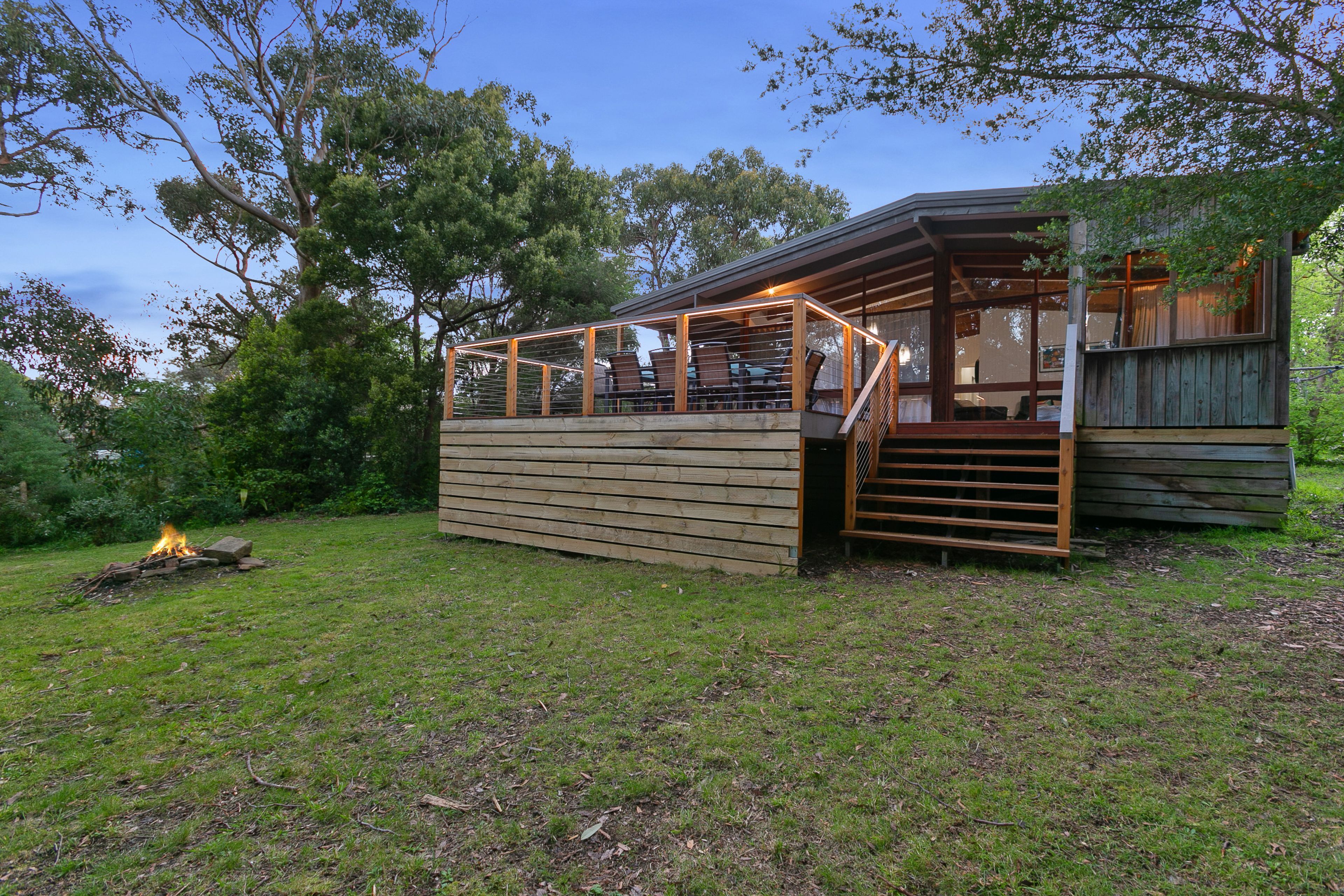 Une structure en bois dotée d’un espace de repos abrité et d’un foyer au premier plan.